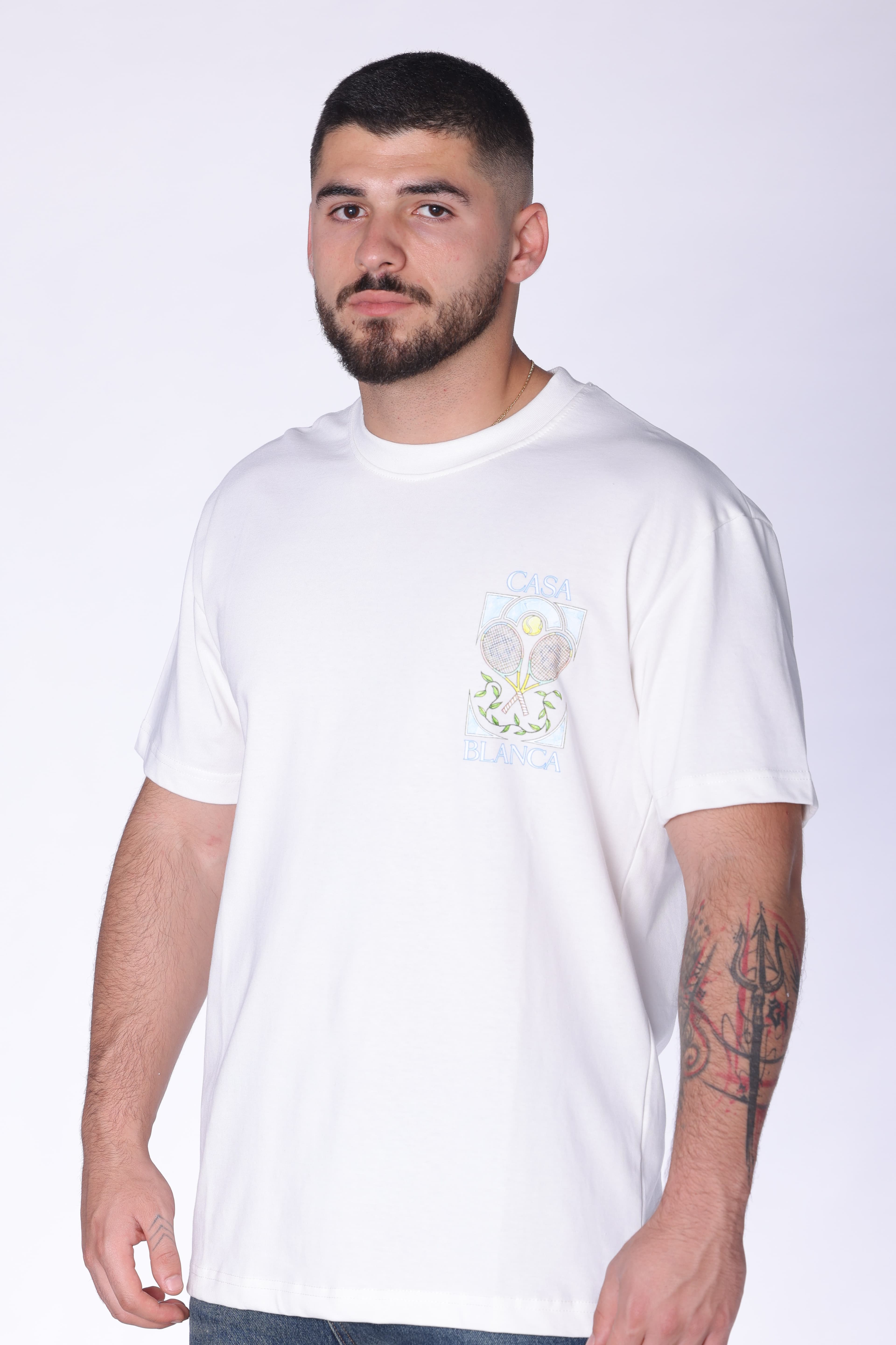 White Oversized T-Shirt Casa Blanca Tennis - Clean white oversized t-shirt featuring a subtle front chest graphic and bold Casa Blanca-inspired artwork on the back with tennis racket design details. Made from soft breathable fabric with a relaxed fit for all-day comfort. A fresh premium streetwear piece perfect for casual summer looks and everyday styling.