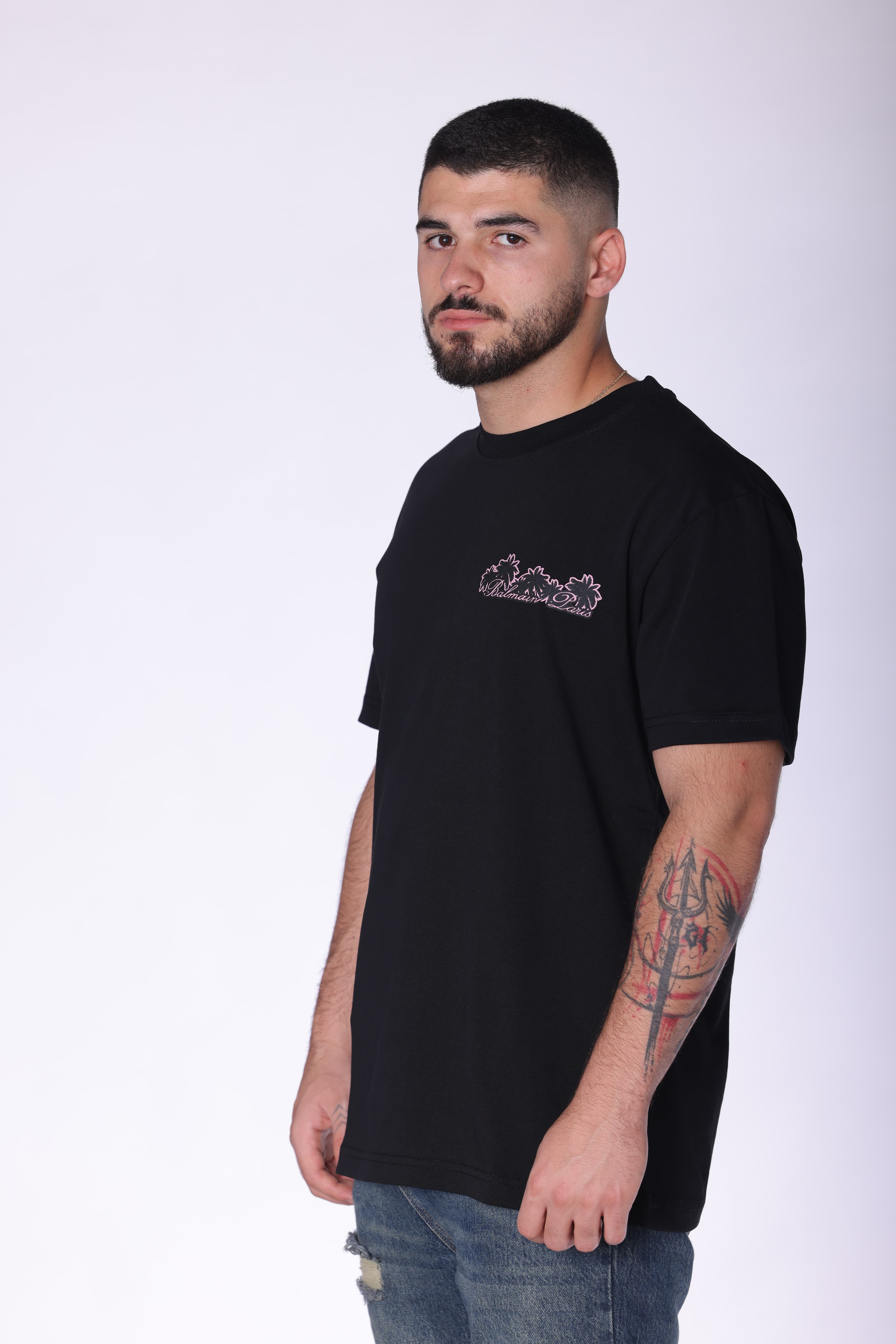 Black Balmain Club Oversized T-Shirt - Black oversized t-shirt featuring a minimal front chest logo and bold Balmain Club Paris-inspired artwork on the back with tropical sunset design details. Made from soft breathable fabric with a relaxed fit for everyday comfort. A standout luxury streetwear piece perfect for summer outfits, casual styling, and elevated everyday wear.