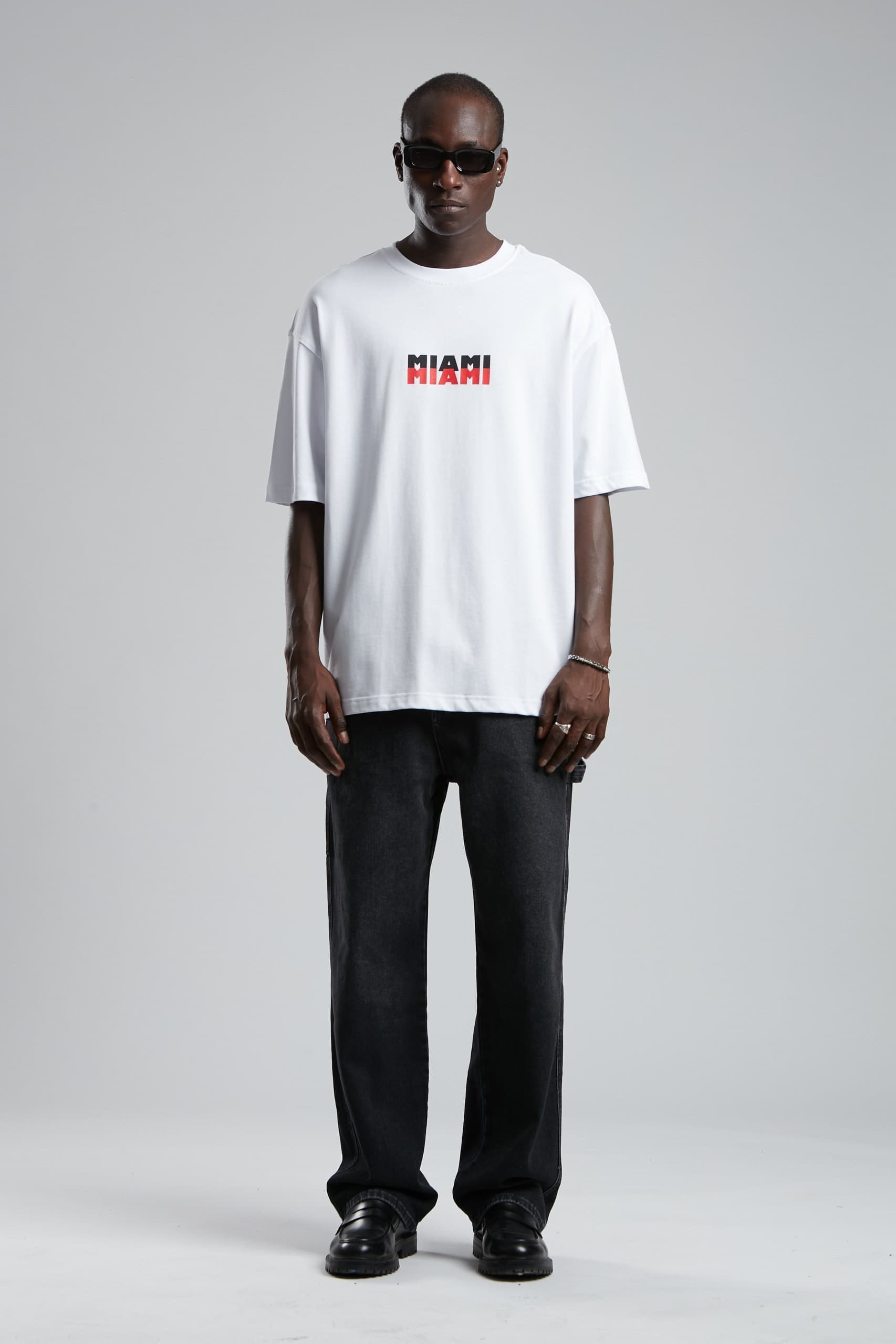 Oversized Miami Palm T-Shirt - Oversized white t-shirt featuring a clean front Miami logo and bold back graphic with palm tree artwork and vintage city-inspired detailing. Crafted from soft breathable fabric with a relaxed fit for all-day comfort. A fresh streetwear essential perfect for summer outfits, casual styling, and everyday wear.