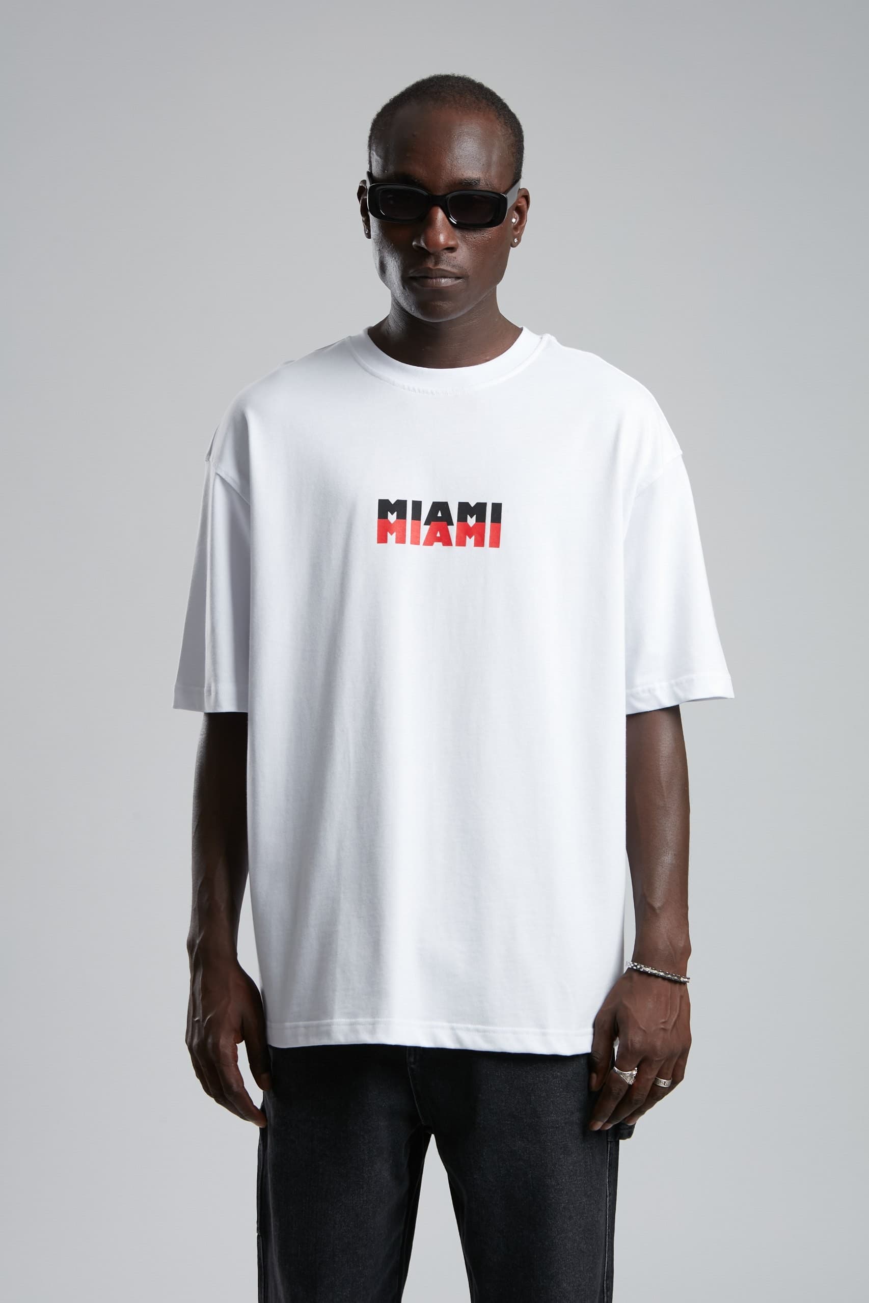 Oversized Miami Palm T-Shirt - Oversized white t-shirt featuring a clean front Miami logo and bold back graphic with palm tree artwork and vintage city-inspired detailing. Crafted from soft breathable fabric with a relaxed fit for all-day comfort. A fresh streetwear essential perfect for summer outfits, casual styling, and everyday wear.