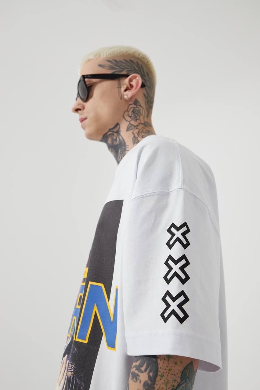 Oversized White Graphic T-Shirt "born" - Oversized white graphic t-shirt featuring a bold vintage-inspired front print with artistic portrait artwork and standout “BORN” lettering in blue with yellow outline. Designed with sleeve cross symbols on both sides and subtle chest detailing for a streetwear edge. Made with a relaxed drop-shoulder fit and soft cotton fabric, perfect for everyday casual looks.