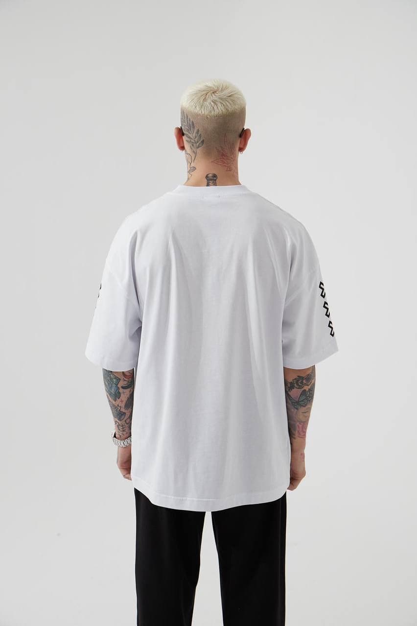 Oversized White Graphic T-Shirt "born" - Oversized white graphic t-shirt featuring a bold vintage-inspired front print with artistic portrait artwork and standout “BORN” lettering in blue with yellow outline. Designed with sleeve cross symbols on both sides and subtle chest detailing for a streetwear edge. Made with a relaxed drop-shoulder fit and soft cotton fabric, perfect for everyday casual looks.