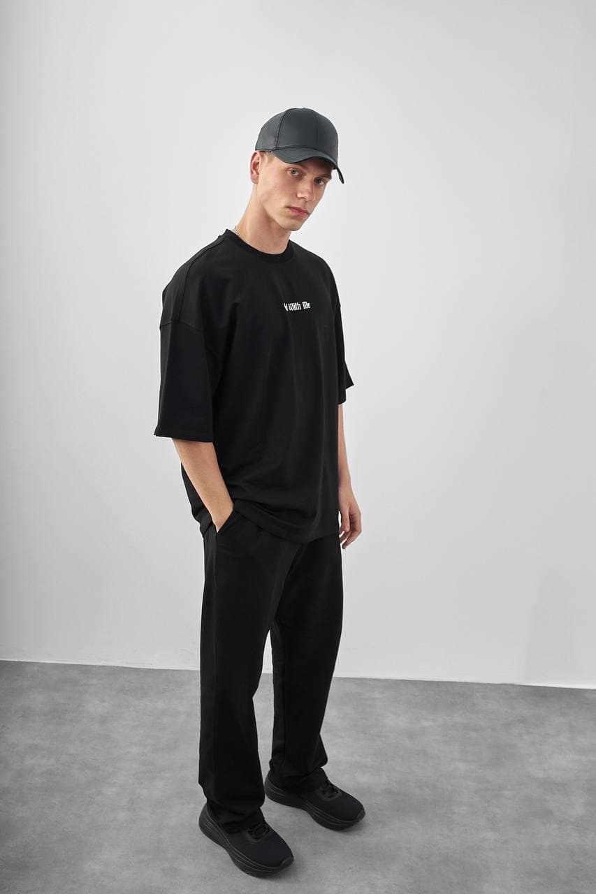 Oversized "god With Me" Black T-Shirt - Oversized black streetwear t-shirt featuring a clean minimal front logo and a bold statement back print with gothic “God With Me” text. Finished with a striking graphic hand design for an edgy urban look. Designed with a relaxed drop-shoulder fit, soft premium fabric, and loose silhouette for everyday comfort and style.