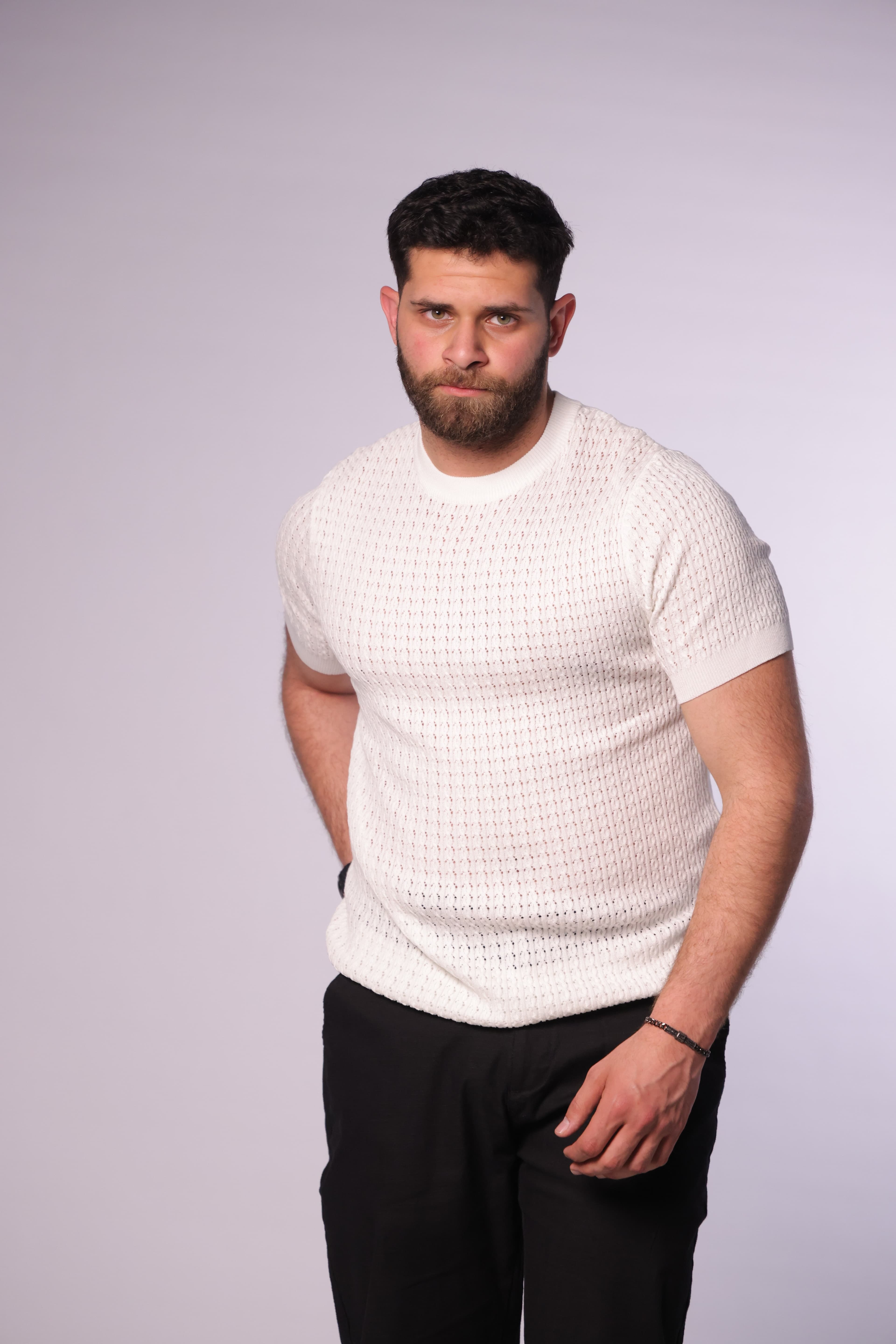 Slim-Fit White Knitted T-Shirt - Slim-fit knitted t-shirt in an elegant white tone, featuring a textured patterned weave that adds depth and a premium feel. Designed with a clean crew neckline and fitted short sleeves that highlight the silhouette. Crafted from soft, breathable fabric, making it perfect for smart-casual looks or elevated everyday wear.