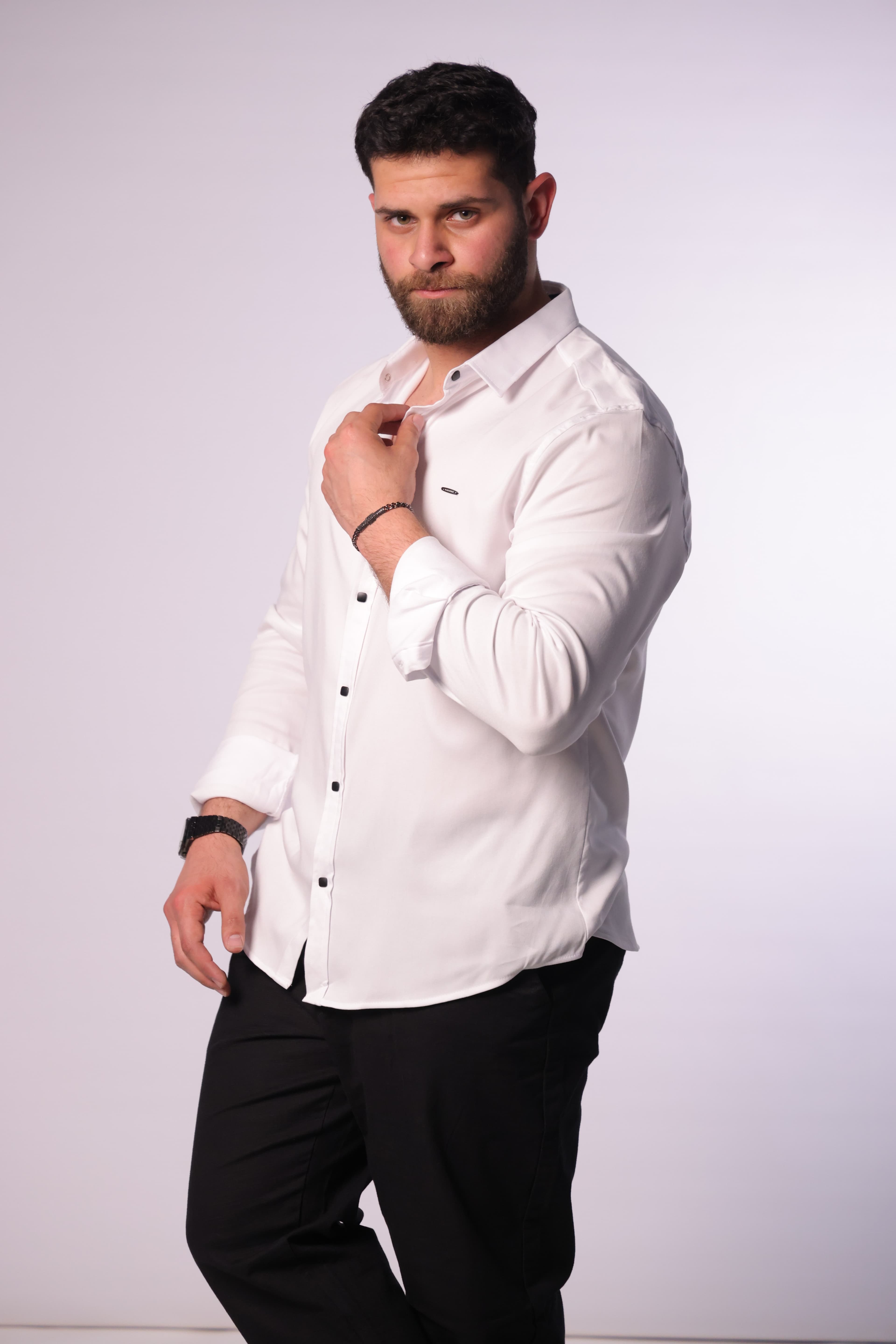 Slim-Fit White Button-Down Shirt - Slim-fit white button-down shirt designed for a clean, modern look. Featuring a sharp collar, minimal chest detailing, and contrasting dark buttons for a refined touch. Crafted from smooth, lightweight fabric that offers comfort and a polished finish—perfect for formal occasions or smart-casual styling.