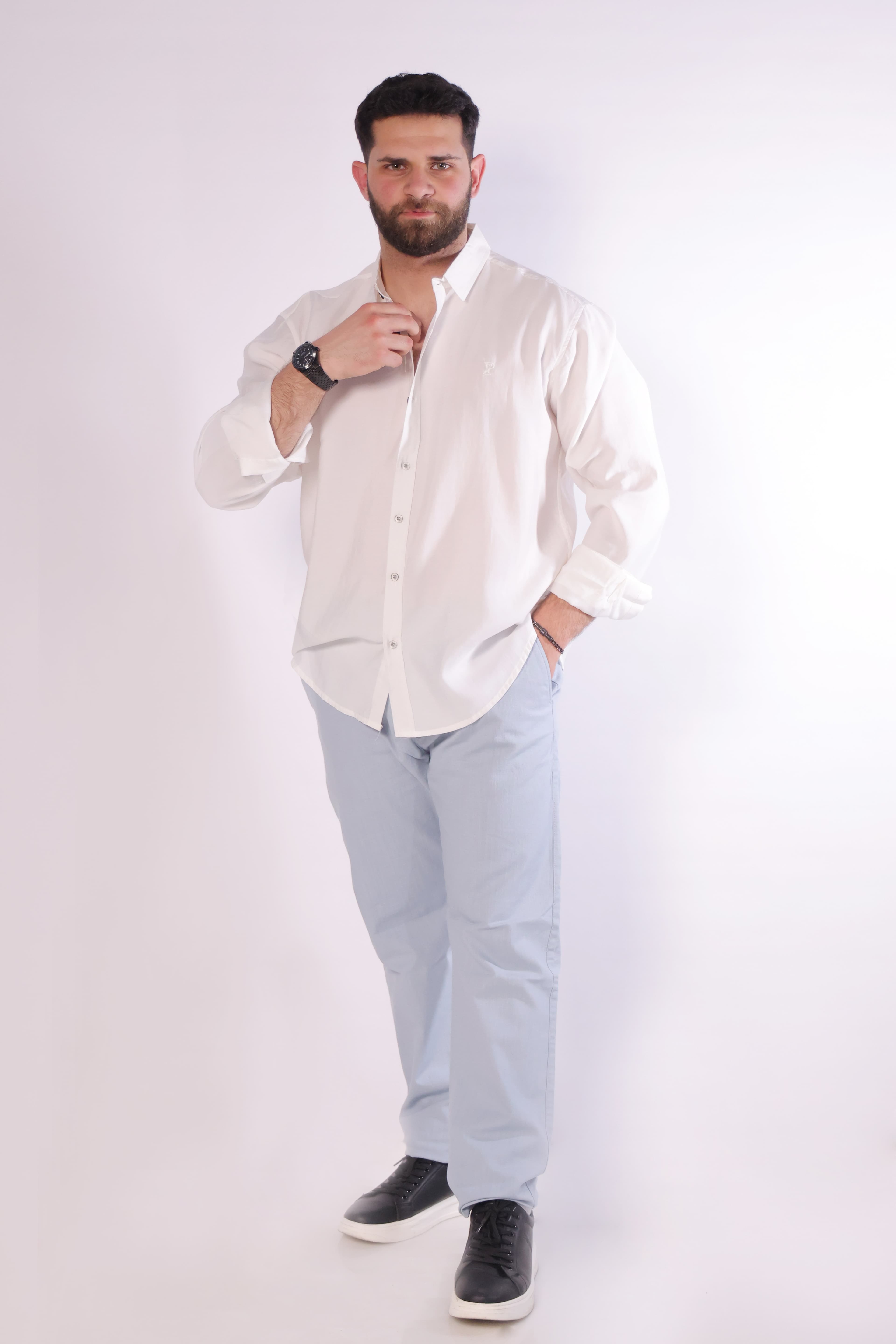 Relaxed-Fit White Button-Down Shirt - Relaxed-fit white button-down shirt designed for a clean and effortless look. Featuring a classic collar, full button closure, and subtle chest logo detailing for a minimal touch. Crafted from lightweight, breathable fabric with a soft feel, making it perfect for smart-casual outfits or laid-back everyday styling.