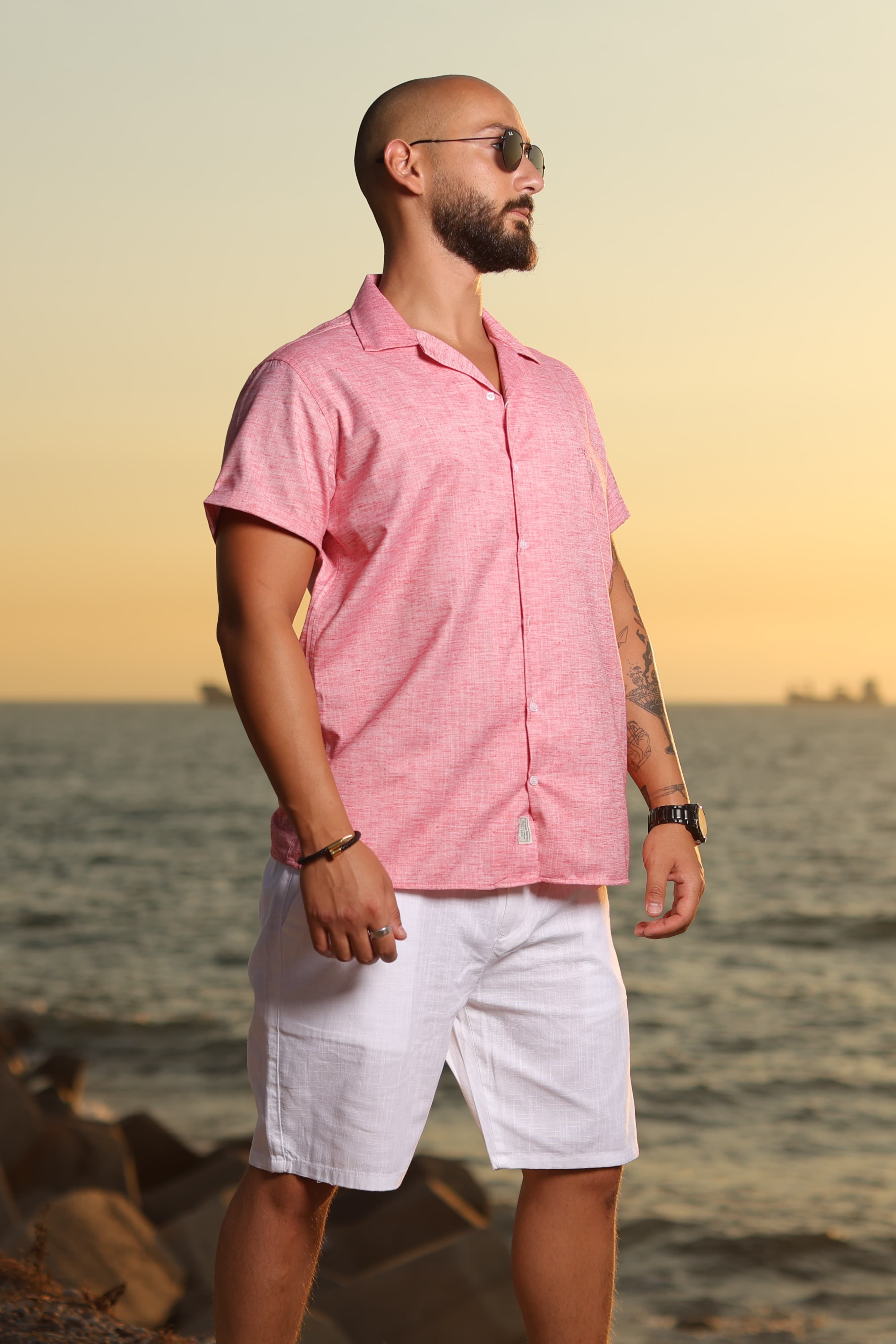 Relaxed-Fit Button-Down Shirt Coral Pink - Relaxed-fit short sleeve button-down shirt in a fresh coral pink tone, featuring a lightweight textured fabric for a breathable, summer-ready feel. Designed with an open camp collar and clean front closure for a laid-back yet refined look. Perfect for warm-weather styling, whether paired with shorts or light trousers for a smart-casual coastal vibe.