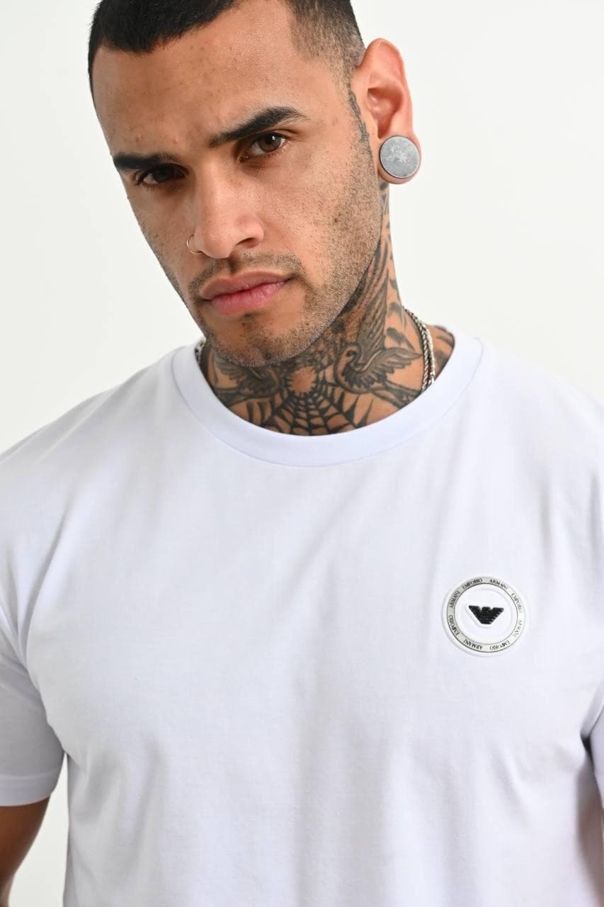 Classic White Premium Tee - Classic white premium tee with a clean minimal design and sleek chest emblem detail. Crafted with a smooth soft-touch fabric and a fitted cut that gives a sharp modern look. Easy to style for both streetwear and casual outfits, whether layered or worn on its own. Timeless, versatile, and made for an everyday luxury vibe.