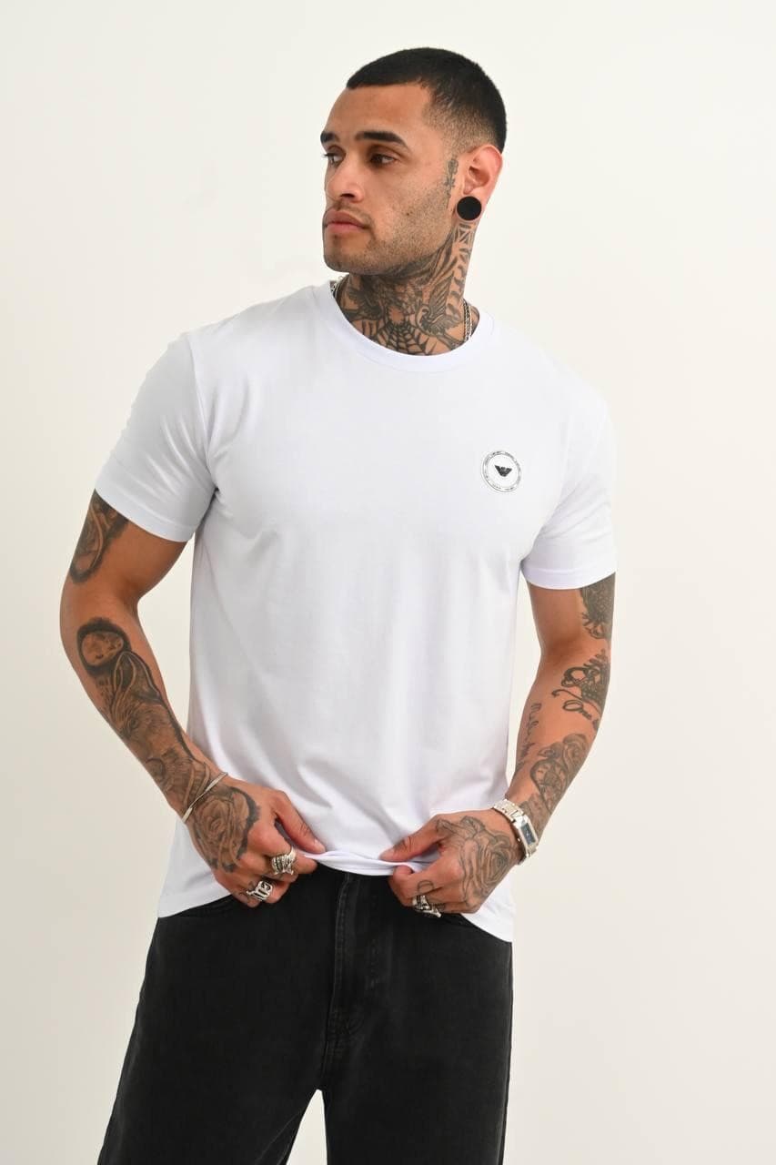 Classic White Premium Tee - Classic white premium tee with a clean minimal design and sleek chest emblem detail. Crafted with a smooth soft-touch fabric and a fitted cut that gives a sharp modern look. Easy to style for both streetwear and casual outfits, whether layered or worn on its own. Timeless, versatile, and made for an everyday luxury vibe.